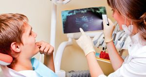 The Bare Bones Of Gum Recession, How to stop receding gums, young boy in dentist chair, exam by a female dental hygienist