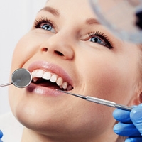 is it better to get braces from a dentist or orthodontist - smiling woman getting teeth checked