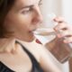 Woman drinking a glass of water to relieve dry mouth