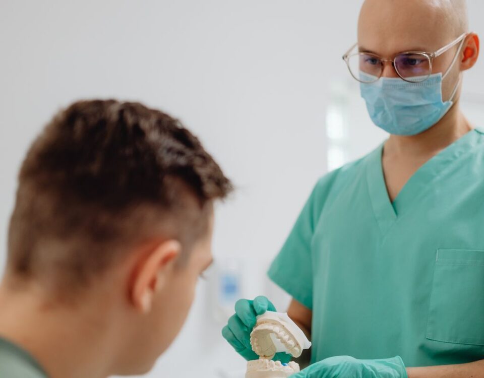 Dentist showing a dental model to a patient while explaining jaw joint problems