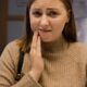 Woman holding her cheek with tooth sensitivity at a dental clinic