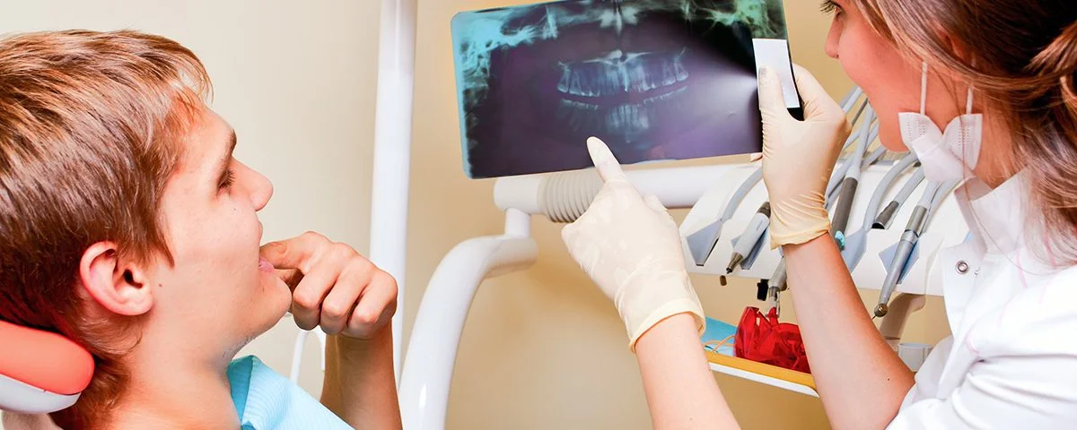 The Bare Bones Of Gum Recession, How to stop receding gums, young boy in dentist chair, exam by a female dental hygienist