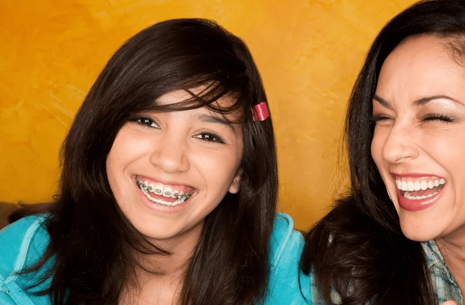 5 Reasons to Choose a Dentist for Braces - mother and daughter smiling together, daughter with braces