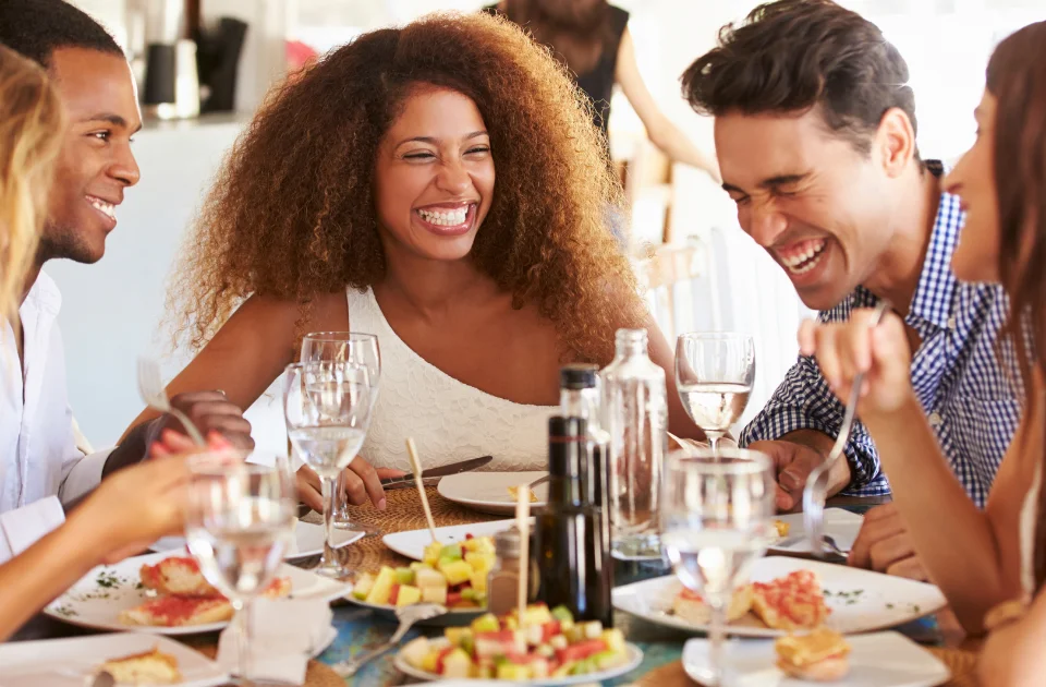 How to Know if You Need Dental Implants - young friends smiling and enjoying a meal together